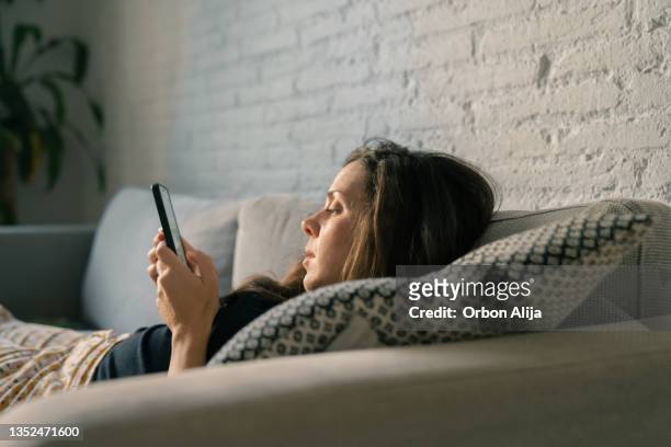 mujer triste usando el teléfono celular - laziness fotografías e imágenes de stock