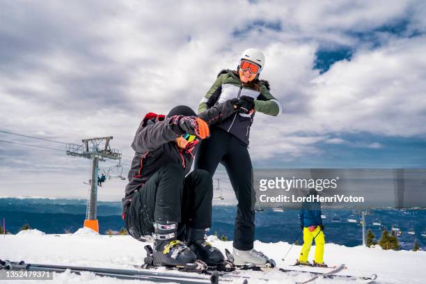 junge frau hilft einem jungen männlichen skifahrer - fallen lord stock-fotos und bilder