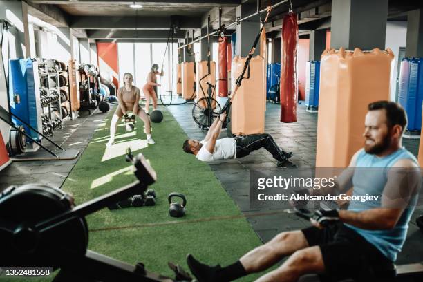 busy sports team occupying cross training gym - rowing machine stock pictures, royalty-free photos & images