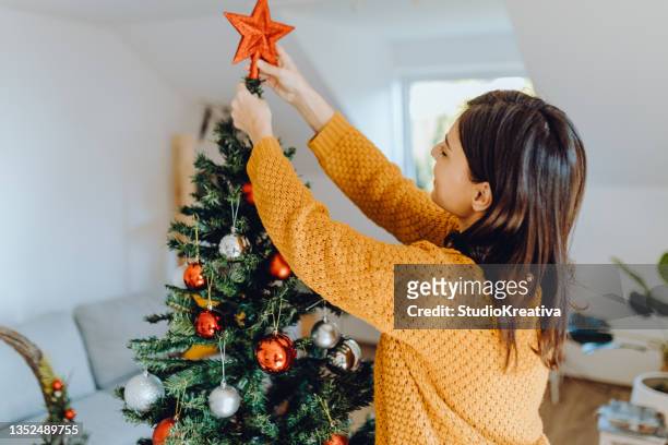 young women decorating her home for christmas - decorating christmas tree stock pictures, royalty-free photos & images