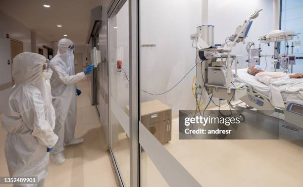 doctors wearing ppe while checking on an isolated patient at the hospital during the pandemic - coronavirus hospital stock pictures, royalty-free photos & images