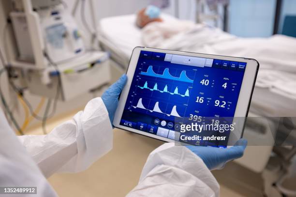 doctor checking the vital signs of a patient hospitalized for covid-19 - icu patient stock pictures, royalty-free photos & images