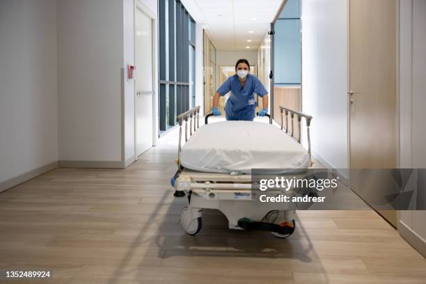 フェイスマスクを着用しながら病院でガーニーを押す看護師 - stretcher ストックフォトと画像