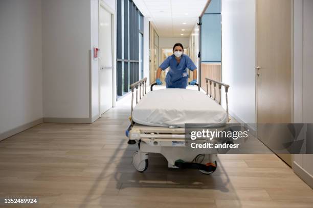 nurse pushing a gurney at the hospital while wearing a facemask - hospital gurney stock pictures, royalty-free photos & images