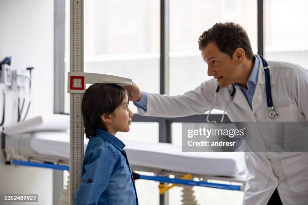 pediatrician examining a boy and measuring his height at the doctor's office - altitude sickness stock pictures, royalty-free photos & images