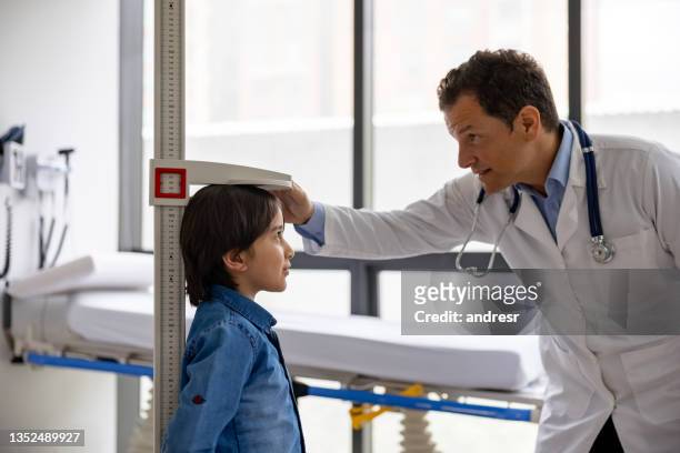pediatrician examining a boy and measuring his height at the doctor's office - high up imagens e fotografias de stock