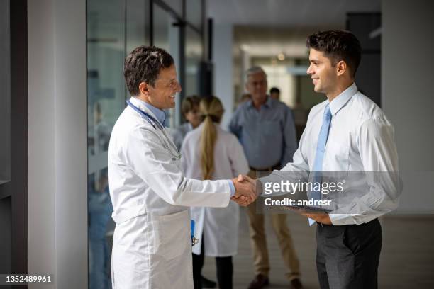 representante médico de ventas saludando a un médico con un apretón de manos en el hospital - oficio de ventas fotografías e imágenes de stock