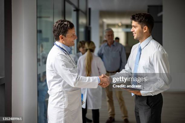 medical sales representative greeting a doctor with a handshake at the hospital - handshake doctor stock pictures, royalty-free photos & images