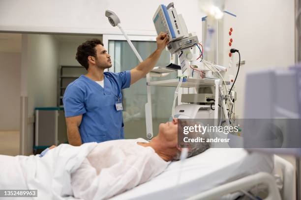 nurse at the hospital checking the vitals on a hospitalized patient - serviço de urgência imagens e fotografias de stock