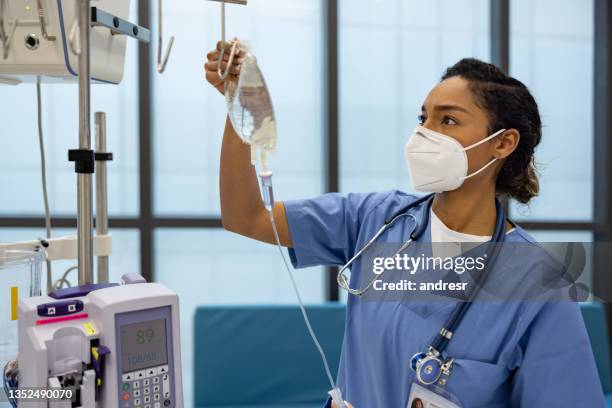 nurse at the hospital putting an iv drip on a patient - máscara de proteção imagens e fotografias de stock