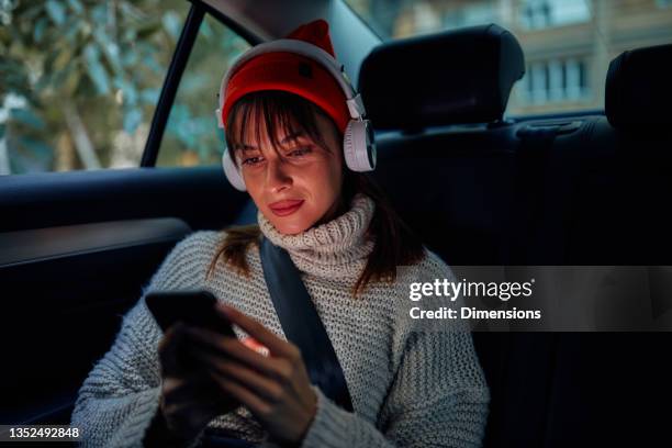 woman listening to music on the backseat of car - car listening to music imagens e fotografias de stock