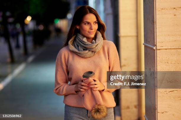 woman with reusable cup walking the street at dusk - beautiful woman winter stock pictures, royalty-free photos & images