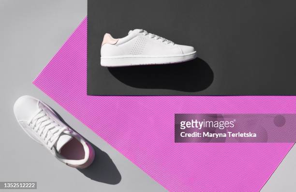 white sneakers on a pink-gray background. - running shoes sky stock-fotos und bilder