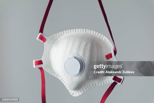 medical used respiratory mask for the face, protecting against the virus, on a gray background. the concept of air pollution, outbreaks of pneumonia, the coronavirus epidemic and the risk of biological contamination. - flu mask stock-fotos und bilder