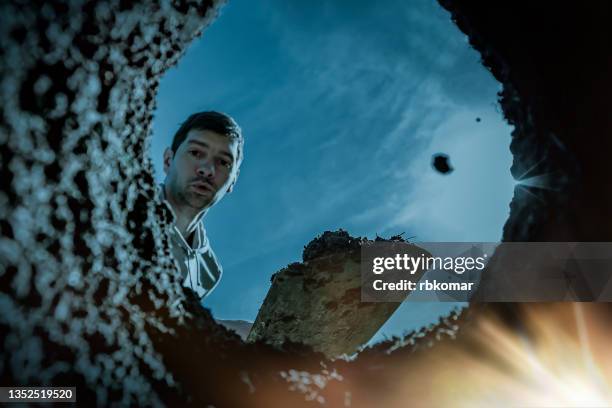 surprised man digger finding glowing treasures in the dirty ground on a dark moonlit night - arqueologo imagens e fotografias de stock