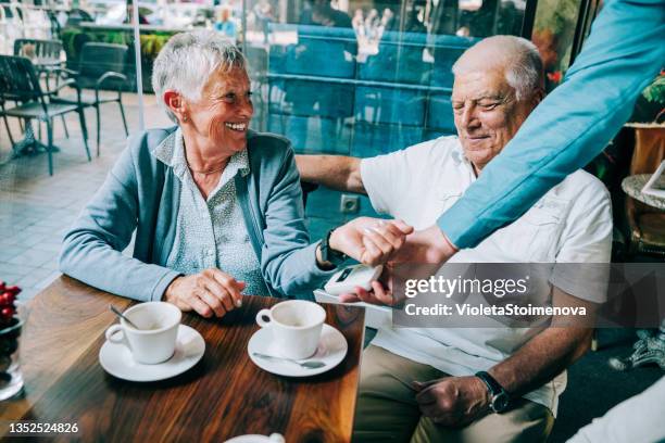 senior woman paying contactless with smart watch at the restaurant. - smartwatch pay stock pictures, royalty-free photos & images