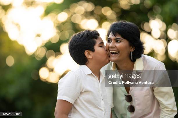 son kissing his mother on the cheek - hispanic month stock pictures, royalty-free photos & images