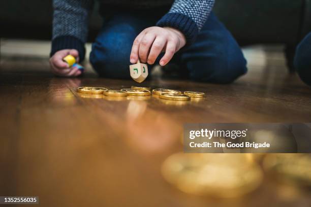 boy playing dreidl game during hanukkah - dreidel stock-fotos und bilder