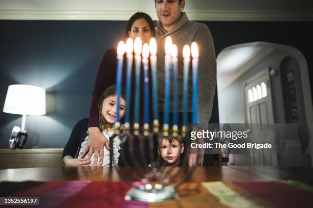 family looking at menorah during hanukkah celebration - chanoeka stockfoto's en -beelden