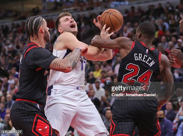 Luka Doncic of the Dallas Mavericks is fouled by Javonte Green of the Chicago Bulls as he drives between Green and Lonzo Ball at the United Center on...