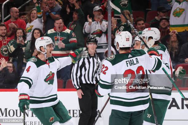 Jon Merrill, Kevin Fiala and Marcus Foligno of the Minnesota Wild celebrate after Foligno scored a goal against the Arizona Coyotes during the first...