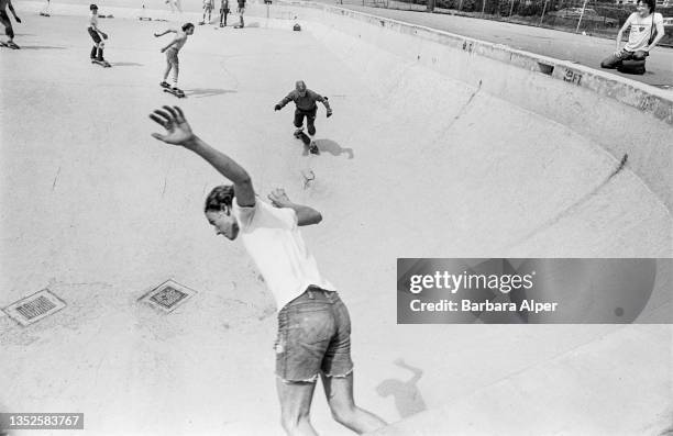 View of teenagers as they ride skateboards in a drained municipal pool, Cambridge, Massachusetts, May 20, 1978.