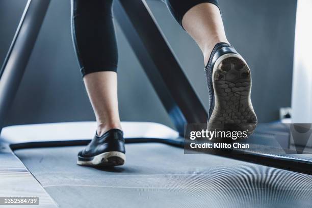 low angle view of woman running on treadmill in a gym - female soles stockfoto's en -beelden