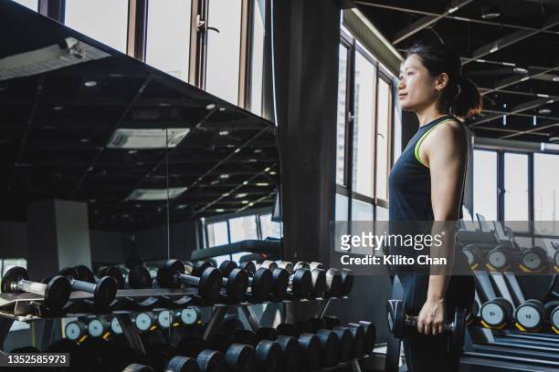 asian woman exercising using dumbbells in a gym - rack stock pictures, royalty-free photos & images