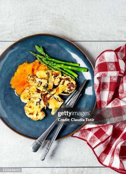 mashed sweet potatoes with roasted cauliflower and steamed asparagus on a plate on white wooden background - mashed sweet potato stock-fotos und bilder