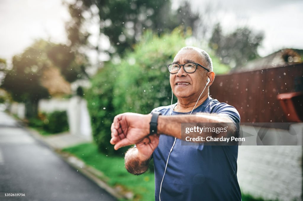 Shot of a senior man standing alone outside and checking his watch after going for a run