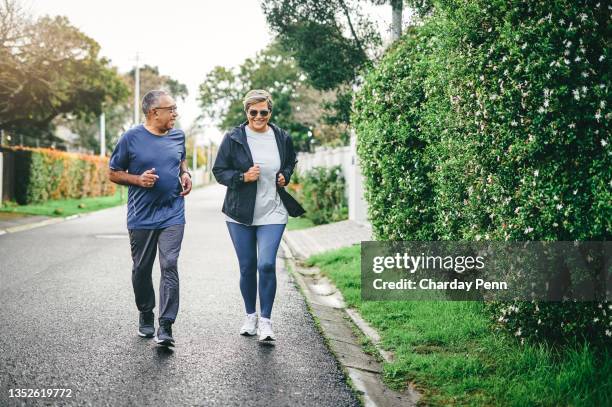 aufnahme eines älteren paares in voller länge, das sich beim laufen im freien zusammenhält - couple running stock-fotos und bilder