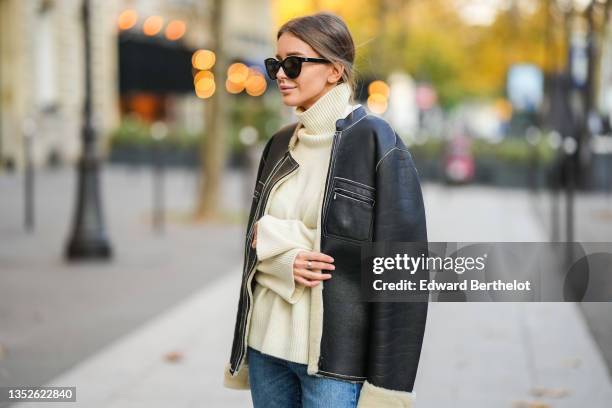 Diane Batoukina @diaanebt wears black sunglasses from Chanel, a white latte cashmere turtleneck pullover from Zara, a black shiny leather with white...