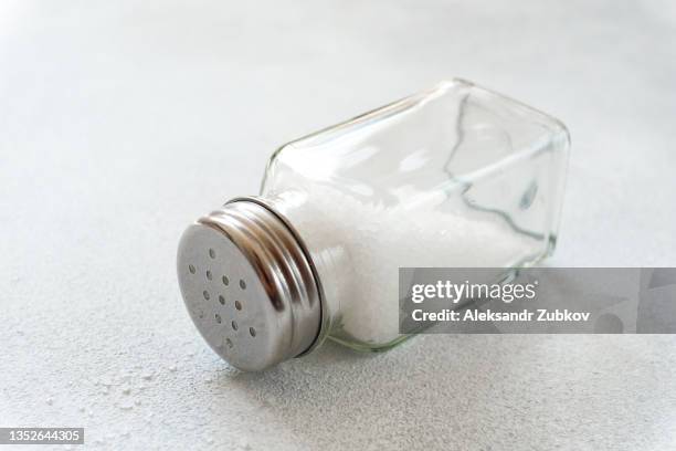 natural, organic, sea, white salt, poured from a fallen salt shaker, on a dining table or background. the concept of cooking healthy food, cosmetology. a copy of the text space. - salt shaker stockfoto's en -beelden