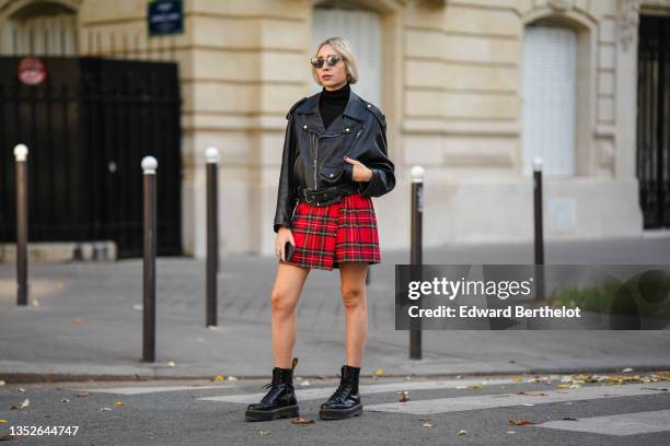 Emy Venturini wears black sunglasses, gold earrings, a black turtleneck pullover from Cos, a black shiny leather oversized vintage biker jacket from...