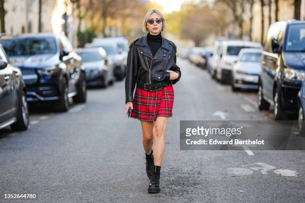 Emy Venturini wears black sunglasses, gold earrings, a black turtleneck pullover from Cos, a black shiny leather oversized vintage biker jacket from...