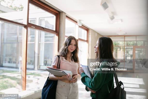 two friends chatting in hallway before going to class - schulheft stock-fotos und bilder