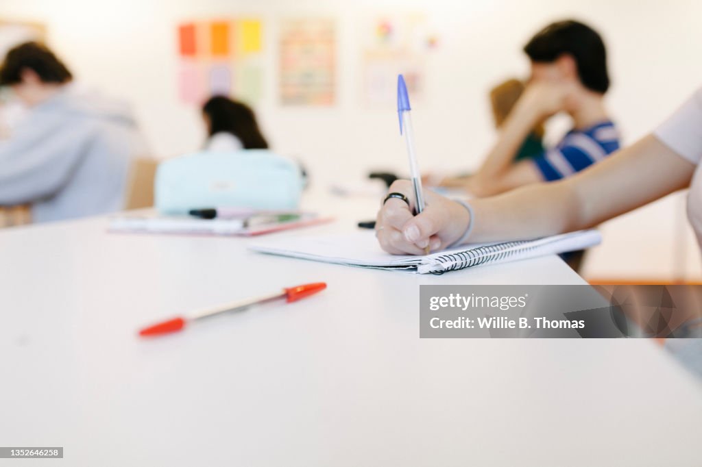 Close Up Of Student Writing In Notepad