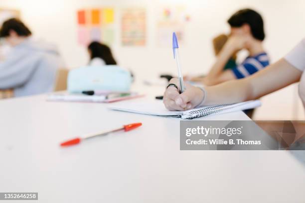 close up of student writing in notepad - schoolgebouw stockfoto's en -beelden