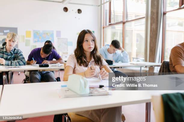 high school student thinking while taking exam - schulkind stock-fotos und bilder