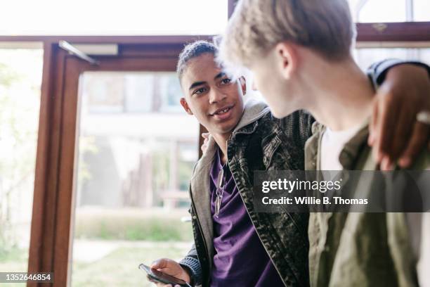 high school student with arm around friend - two boys talking fotografías e imágenes de stock