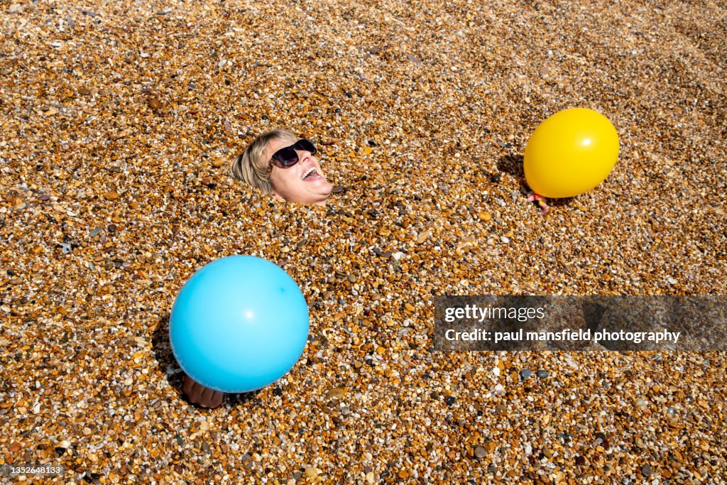 Lady buried in pebbles on beach