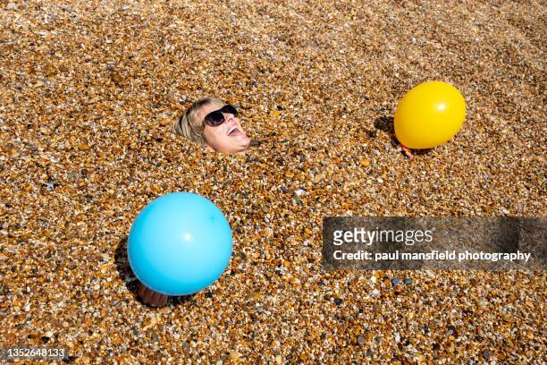 lady buried in pebbles on beach - water's edge stock pictures, royalty-free photos & images