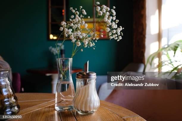 an antique wooden table, a sofa, a bouquet of flowers in a stylish vase and a sugar bowl and a teapot for brewing tea. preparation for the event, coffee break. stylish, fashionable, modern design of a cafe, restaurant, cafeteria or pizzeria. - flowers vase ストックフォトと画像