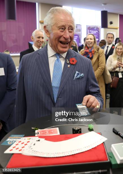 Prince Charles, Prince Of Wales laughs as magician Chris Wall showcases his business success story by playing a trick on the Prince by reading his...