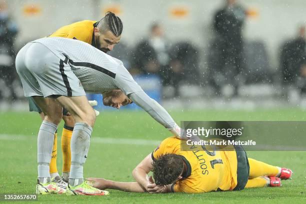 Mathew Ryan of Australia assists Harry Souttar of Australia before he receives treatment during the FIFA World Cup AFC Asian Qualifier match between...