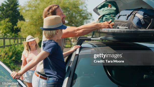 family taking luggage into top box on car in rural area - car camping luggage stock pictures, royalty-free photos & images