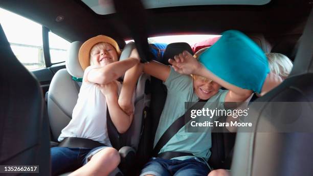 three boys play fighting in back of car - rough housing stockfoto's en -beelden