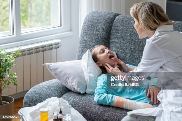 female doctor visiting teenage girl at home - girl tongue doctor stockfoto's en -beelden