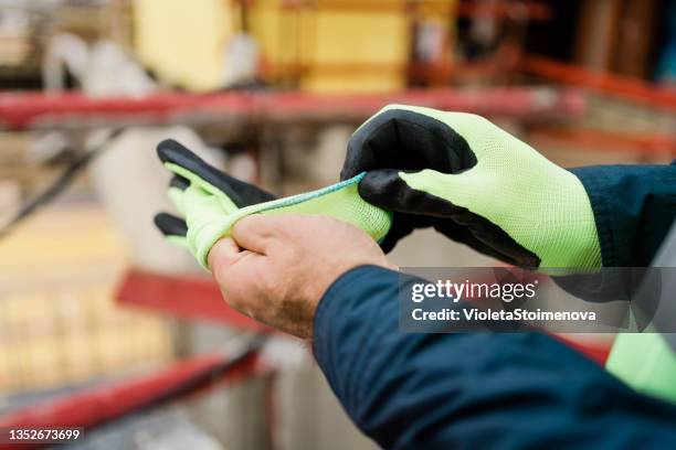 obrero en obra poniéndose guantes. - glove fotografías e imágenes de stock