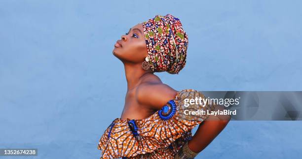 shot of a beautiful young woman wearing traditional african clothing against a blue background - head tie stock pictures, royalty-free photos & images